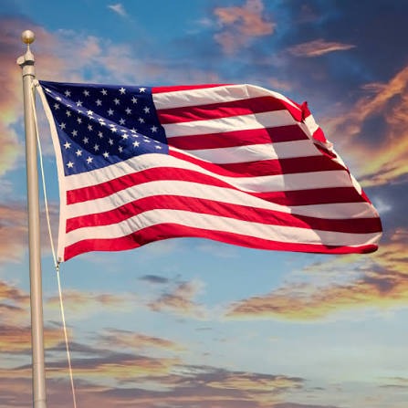 American flag waving against a sunset sky